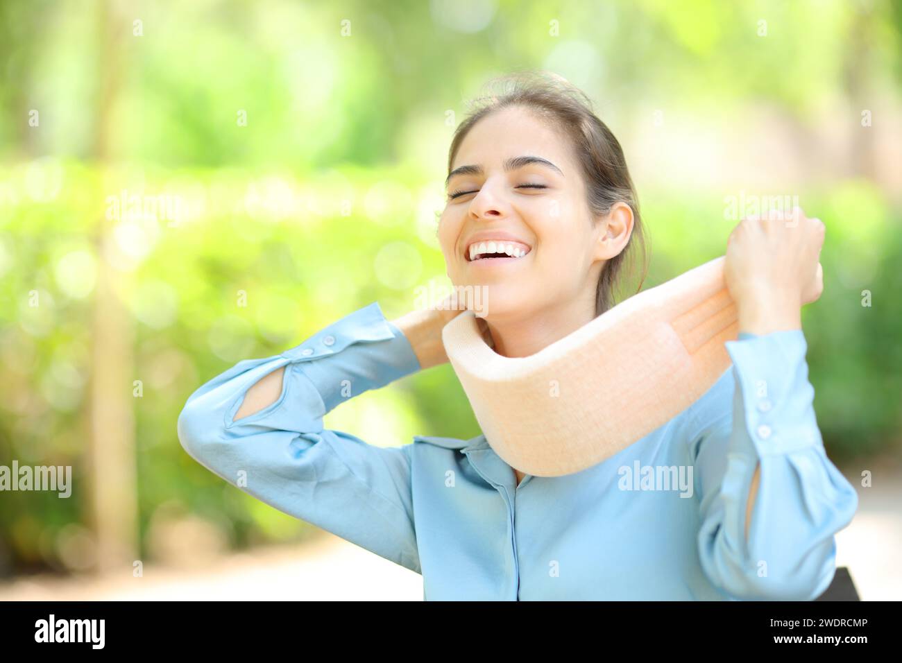Femme heureuse enlevant l'attelle du cou après convalescence dans un parc Banque D'Images
