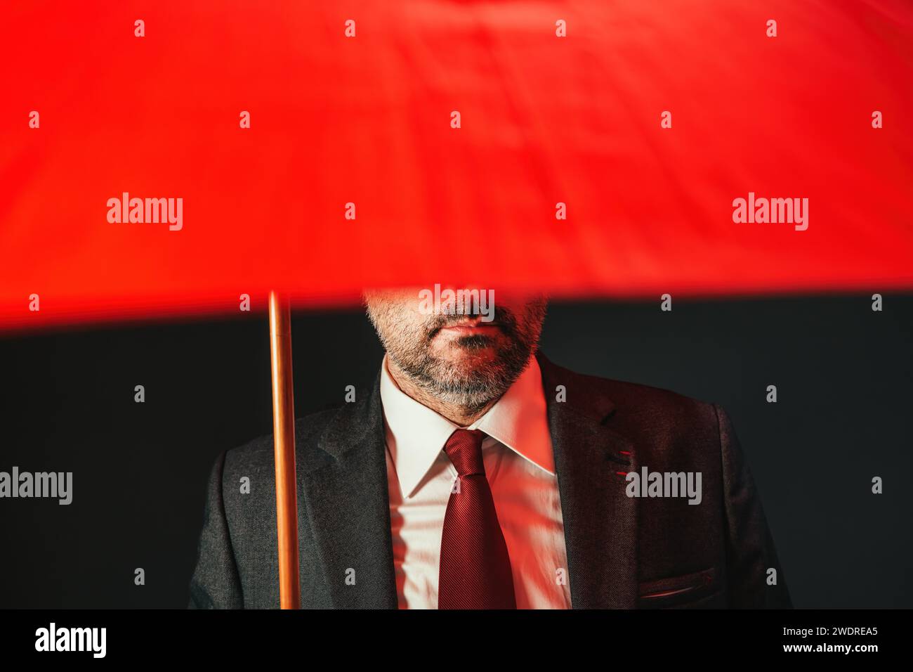 Homme d'affaires sous parapluie rouge, clé basse avec focalisation sélective Banque D'Images