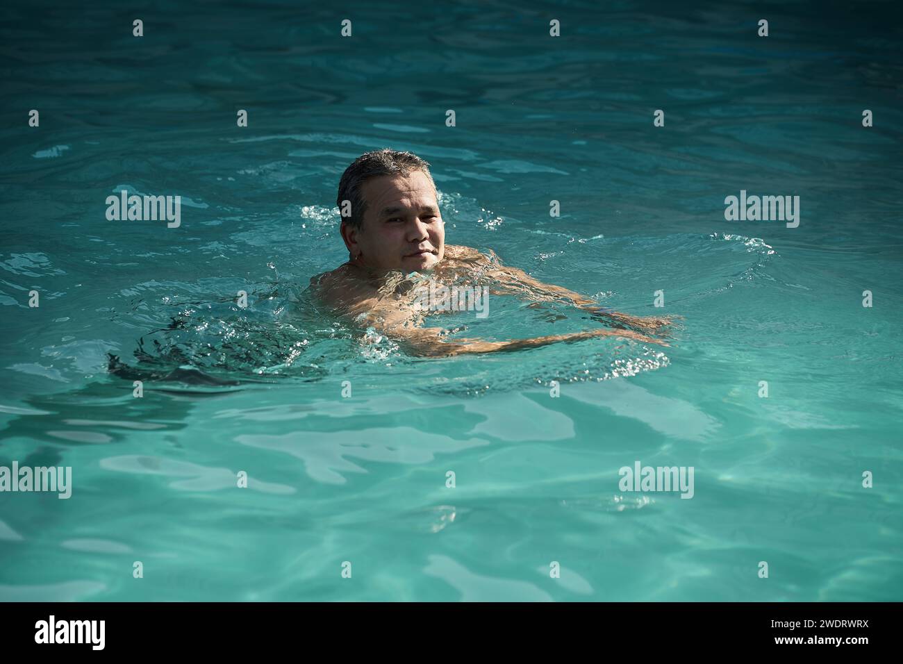 Homme asiatique se baigne dans la piscine de sources chaudes par temps froid Banque D'Images