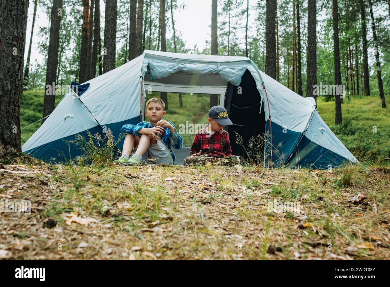 mignons garçons caucasiens assis à l'intérieur d'une grande tente touristique. Concept de camping familial Banque D'Images