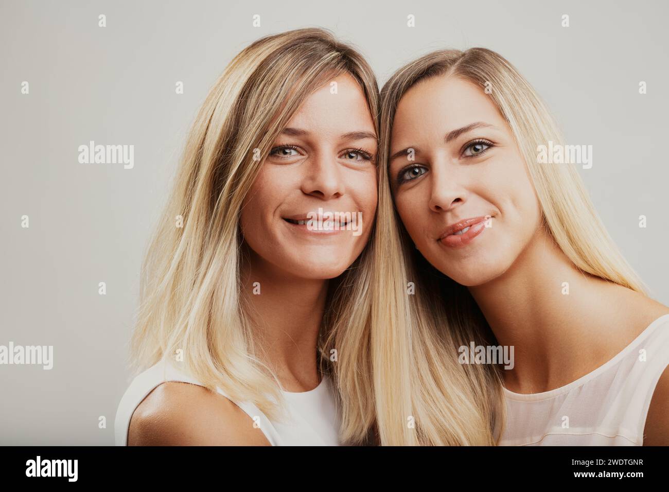 Les femmes blondes, peut-être des frères et sœurs, partagent un moment joyeux, affectueusement enveloppé dans une étreinte Banque D'Images