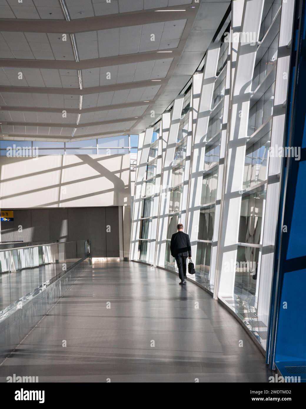 Un homme d'affaires international en costume descend une salle vide de l'aéroport de Calgary Banque D'Images