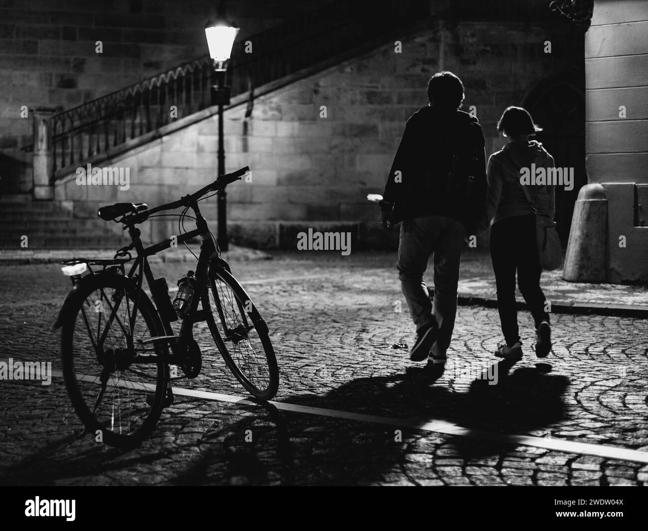 vélo et couple sur la vieille rue de la ville la nuit Banque D'Images
