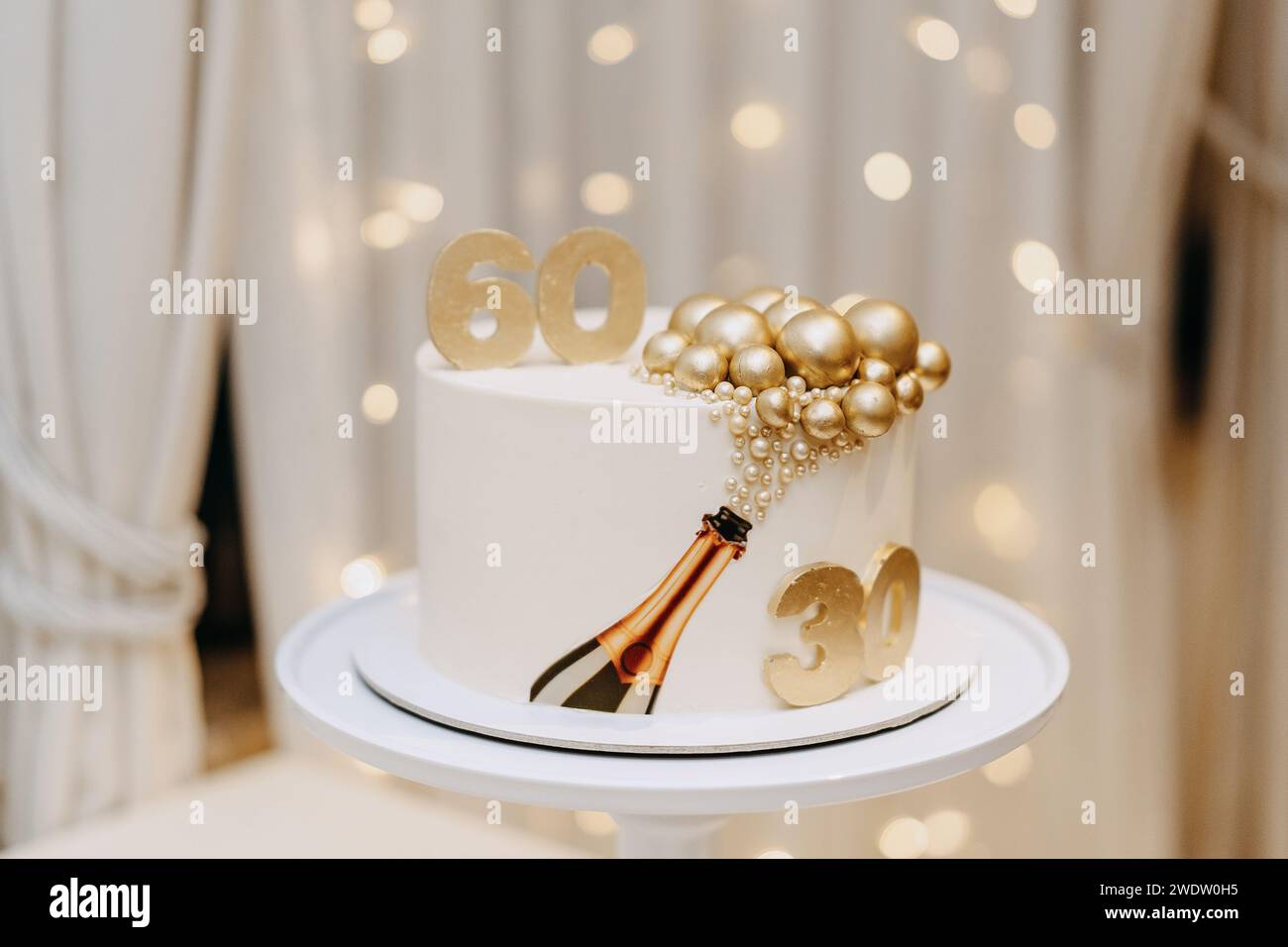 Un délicat gâteau blanc placé sur un support élégant, accompagné d'un éclairage doux et de rideaux gracieux Banque D'Images