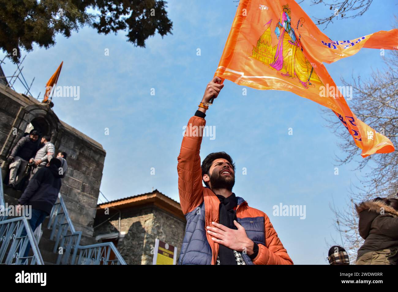 Un dévot hindou tient un drapeau religieux au temple Shankaracharya à l'occasion de la cérémonie de consécration du temple Ayodhya RAM. Lundi après-midi, le Premier ministre Narendra Modi a achevé le « pran pratishtha », ou consécration, du temple RAM à Ayodhya. La cérémonie spéciale pour le temple, qui est encore en construction, a été un effort de plusieurs décennies dans la construction. Pour les hindous, le site marque le lieu de naissance de Lord RAM, l'une des divinités les plus vénérées de la foi hindoue. Mais le site est également vénéré par les musulmans pour avoir abrité la mosquée Babri du 16e siècle, un monument de la foi pour Indi Banque D'Images