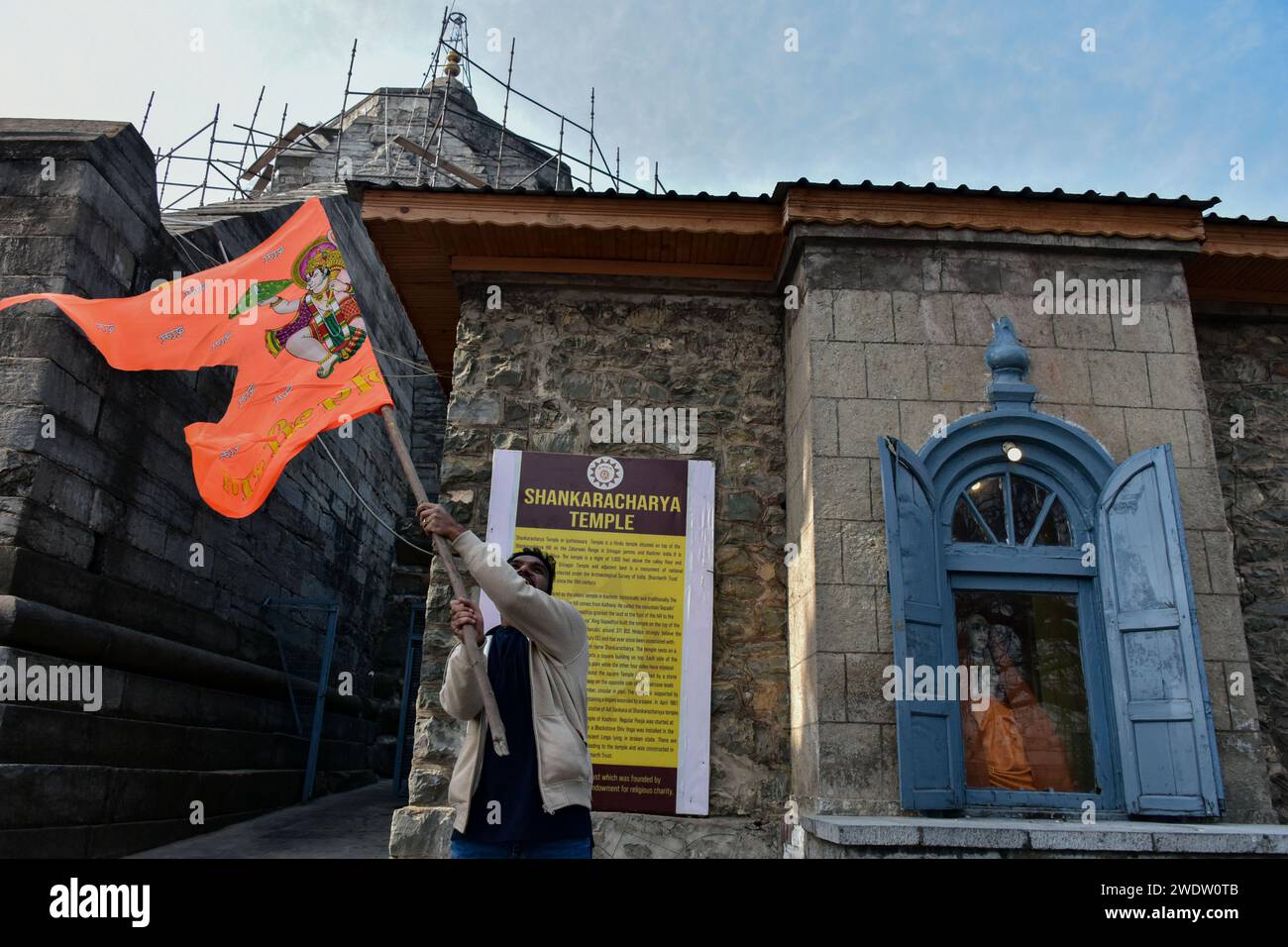 Un dévot hindou tient un drapeau religieux au temple Shankaracharya à l'occasion de la cérémonie de consécration du temple Ayodhya RAM. Lundi après-midi, le Premier ministre Narendra Modi a achevé le « pran pratishtha », ou consécration, du temple RAM à Ayodhya. La cérémonie spéciale pour le temple, qui est encore en construction, a été un effort de plusieurs décennies dans la construction. Pour les hindous, le site marque le lieu de naissance de Lord RAM, l'une des divinités les plus vénérées de la foi hindoue. Mais le site est également vénéré par les musulmans pour avoir abrité la mosquée Babri du 16e siècle, un monument de la foi pour Indi Banque D'Images