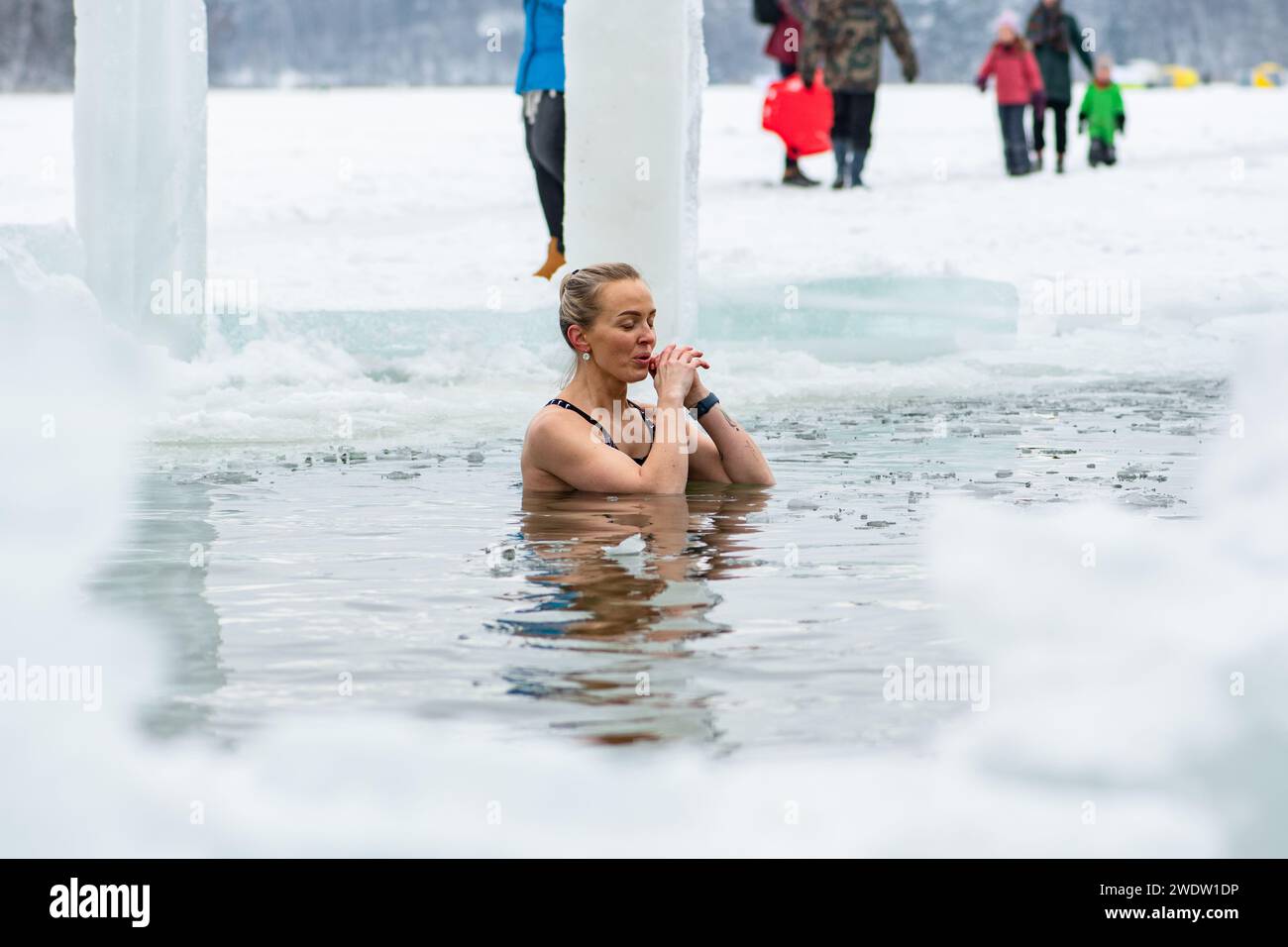Belle fille de cheveux blonds ou femme baignant de glace dans l'eau froide glaciale d'un lac gelé. Méthode Wim Hof, thérapie par le froid, techniques respiratoires, yoga Banque D'Images