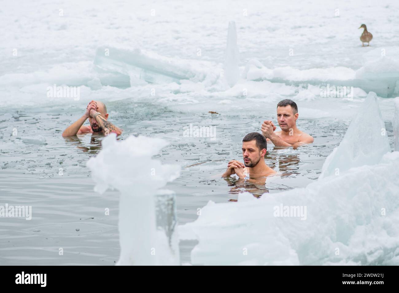 Groupe de garçons ou d'hommes baignant dans l'eau froide glaciale d'un lac gelé. Méthode Wim Hof, thérapie par le froid, techniques de respiration, yoga et méditation Banque D'Images