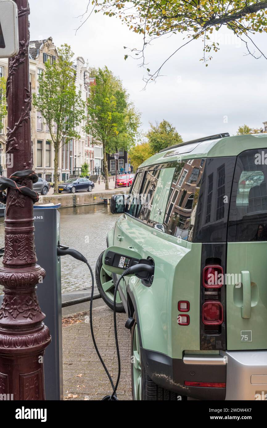 Recharge hybride rechargeable électrique Land Rover Defender sur le côté du canal à Keizergracht à Amsterdam, Hollande. Banque D'Images