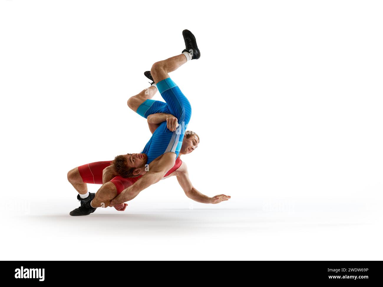 Deux jeunes athlètes, lutteurs qualifiés en uniforme rouge et bleu combattant en mouvement sur fond de studio blanc. Banque D'Images