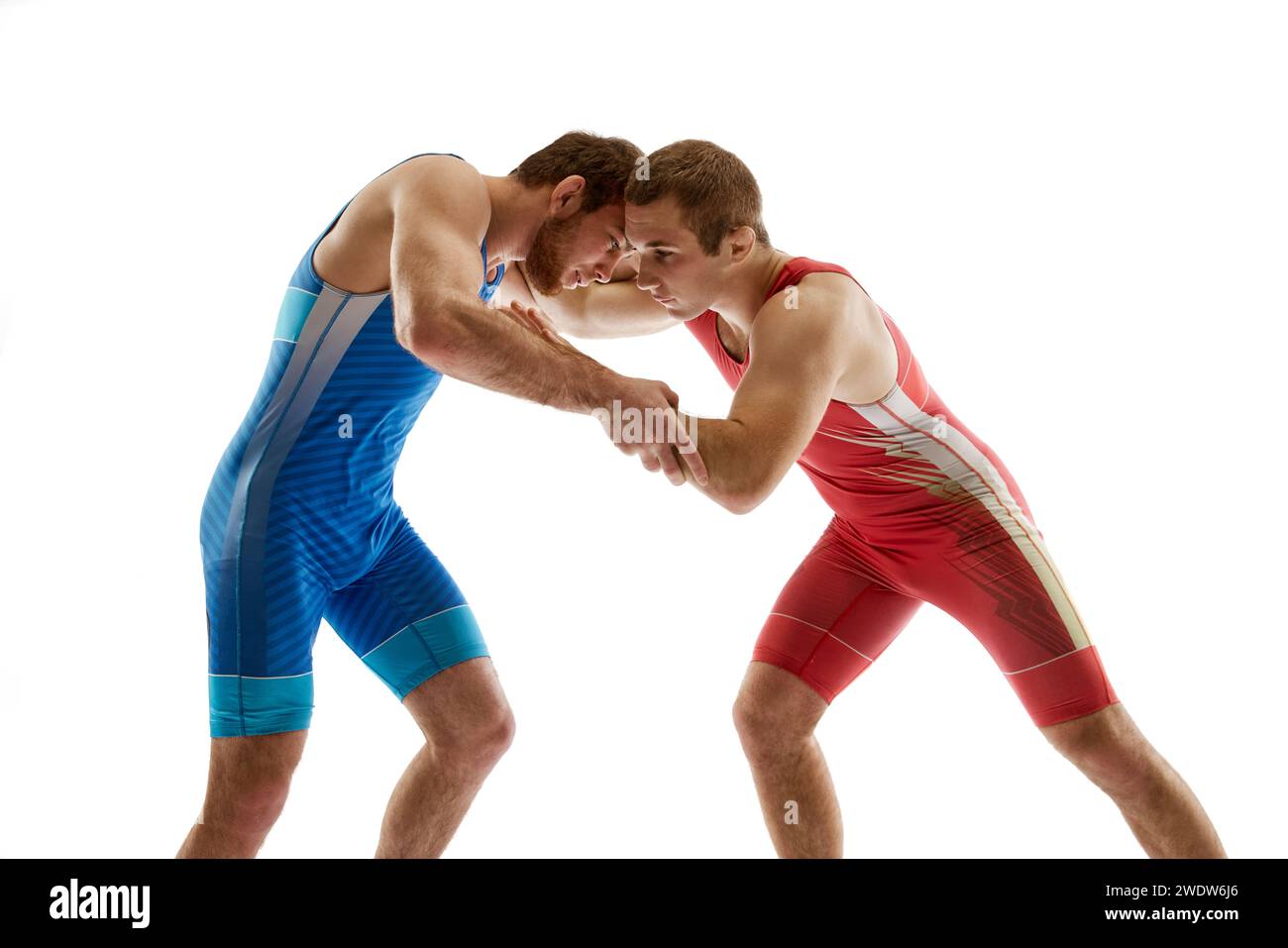Jeunes lutteurs qualifiés en uniforme bleu et rouge combattant main en position neutre sur leurs pieds sur fond de studio blanc. Banque D'Images