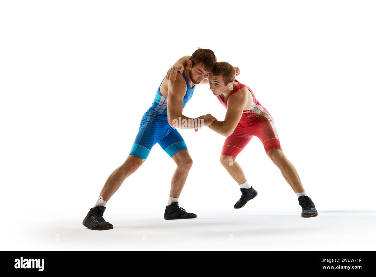 Jeune athlète homme, lutteurs en bleu et rouge uniforme lutte à la main en mouvement sur fond de studio blanc. Banque D'Images