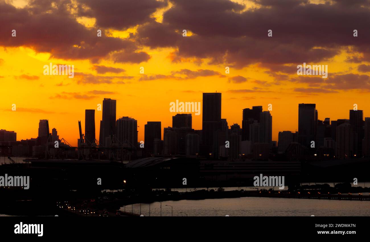 Panorama coucher de soleil silhouette du centre-ville de Miami depuis South Beach avec gratte-ciel et terminal de croisière contre le ciel orange du soleil couchant Banque D'Images