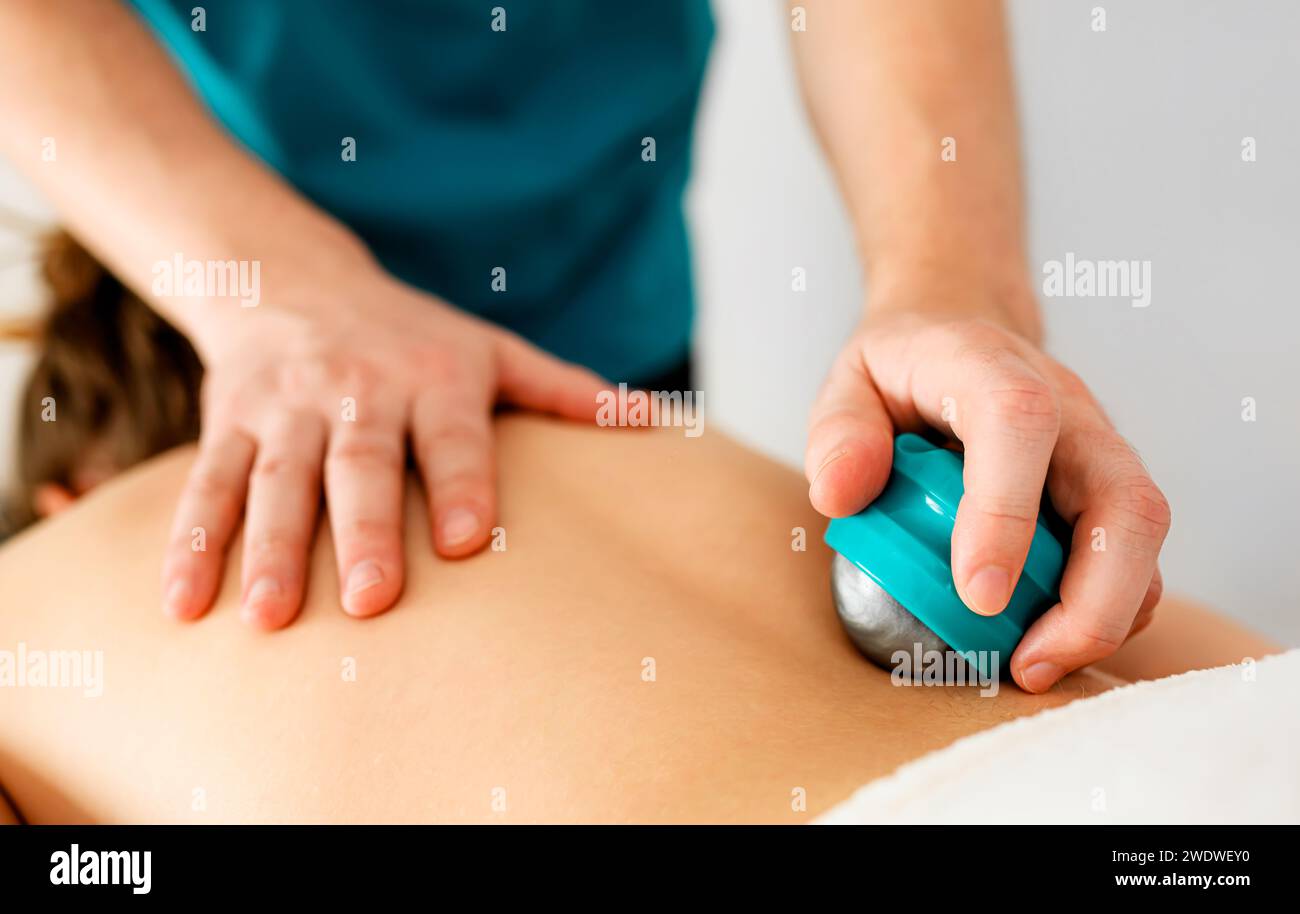 Les mains d'un massothérapeute qualifié font un massage du dos avec des accessoires de massage spéciaux dans un salon de massage Banque D'Images