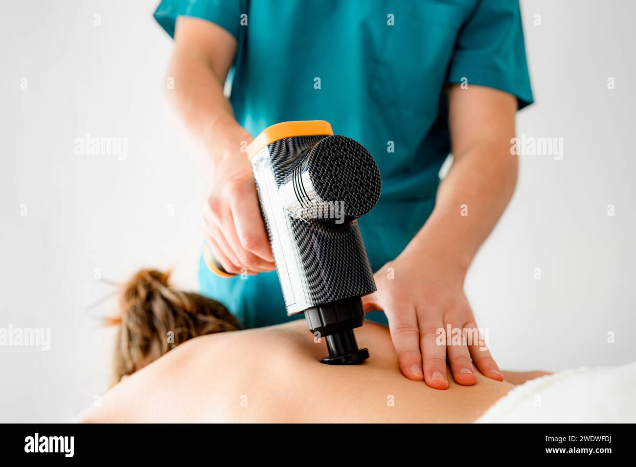Massothérapeute professionnel réhabilitologue faisant un massage du dos avec un masseur vibrant, relaxation des muscles spasmés Banque D'Images