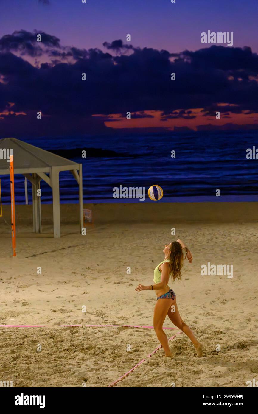 Un groupe d'amis jouant à une partie de Beach volley sur le sable de tel Aviv, plage méditerranéenne dans la soirée au crépuscule Banque D'Images