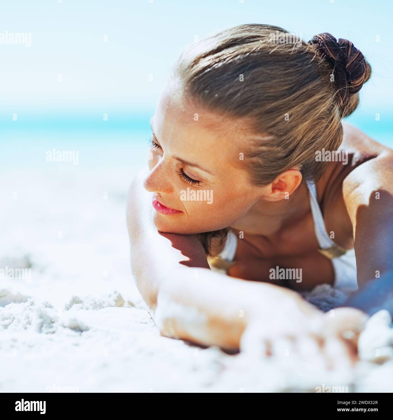 Jeune femme détendue en maillot portant sur une plage de sable Banque D'Images