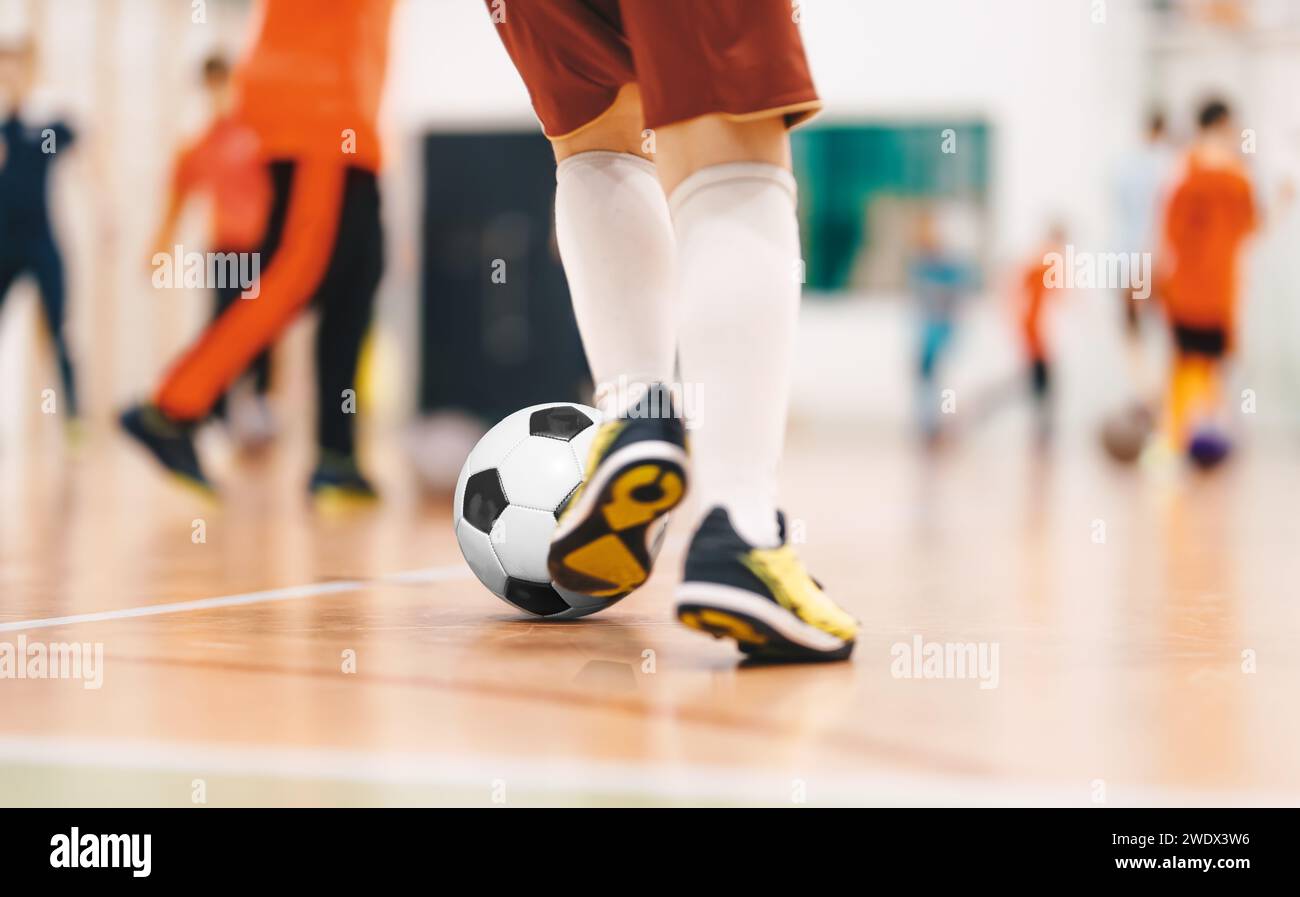 Joueurs dans l'entraînement de futsal. Cours de football en salle pour les enfants à la salle des sports de l'école. Enfants Kicking balles de football sur plancher de futsal en bois Banque D'Images