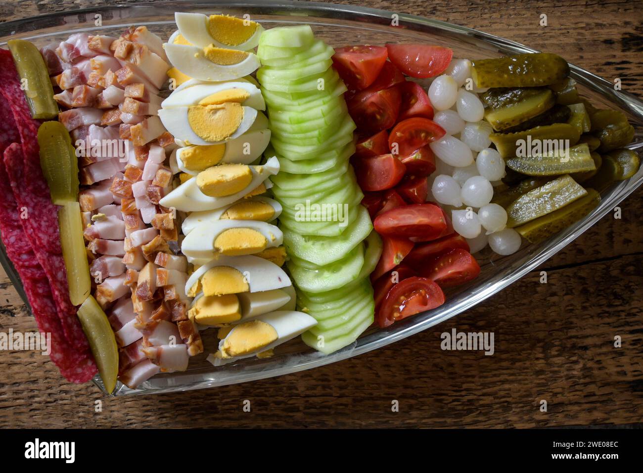 bol doublé plein de nourriture, oeuf, bacon, concombre, salami, tomate, oignon sur un fond en bois. Banque D'Images