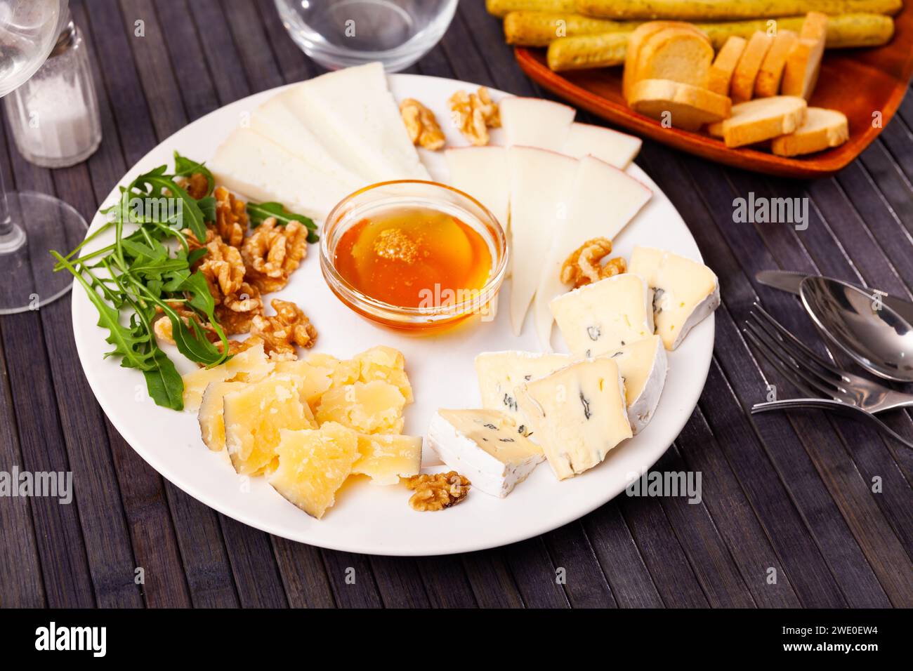 Différents types de fromage tranchés et servis sur une assiette avec un bol de miel, des noix Banque D'Images