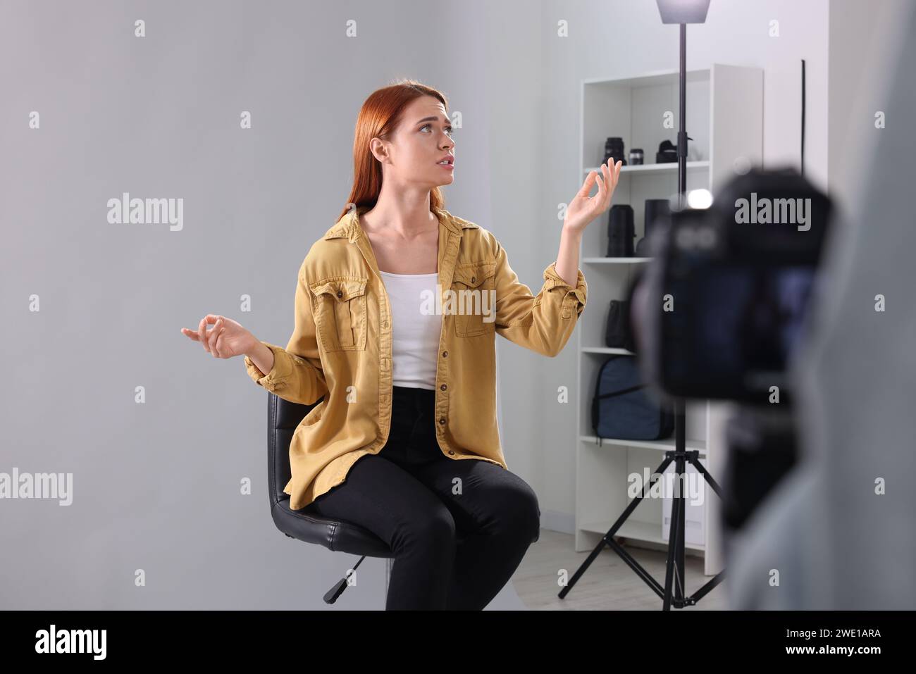 Appel de casting. Femme jouant pendant que le caméraman la filme sur fond gris clair en studio Banque D'Images