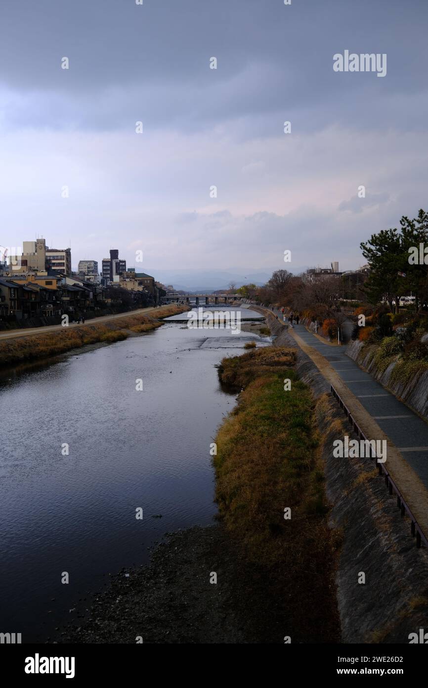 Paysage riverain calme à Kyoto, avec ciel couvert et montagnes au loin. Banque D'Images