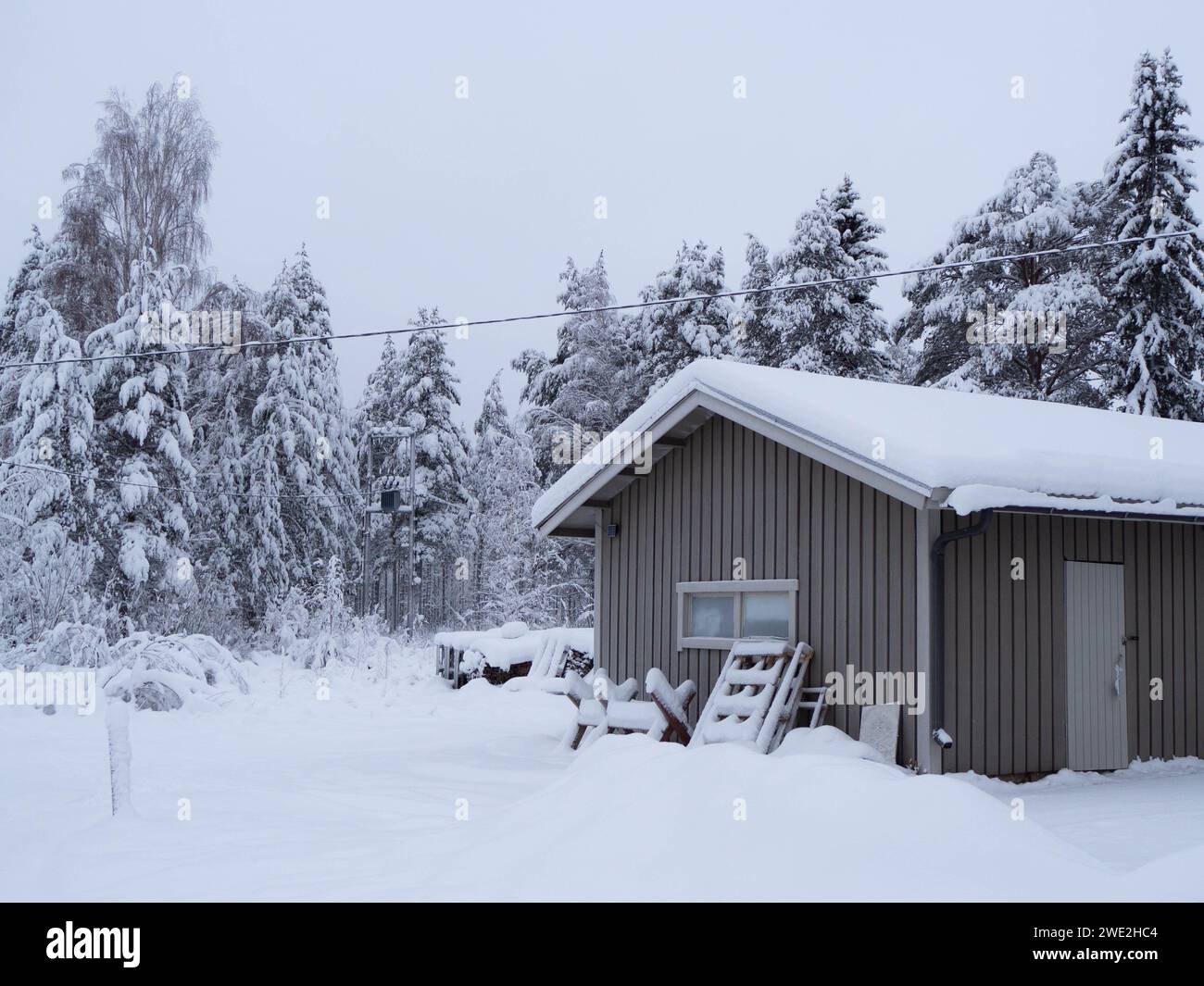 Cabane enneigée au milieu d'une paisible forêt d'hiver à Rovaniemi, en Finlande, mettant en valeur la beauté sereine du paysage arctique Banque D'Images