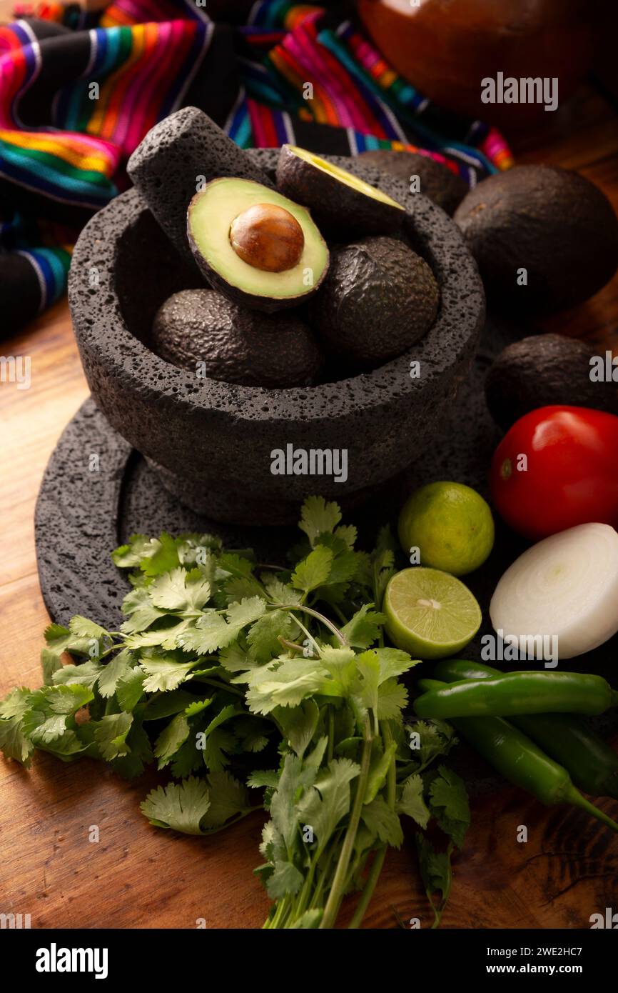 Ingrédients de base pour préparer une trempette à l'avocat connue sous le nom de guacamole faite dans un molcajete de pierre volcanique, une sauce à base d'avocat très populaire. Recette traditionnelle Banque D'Images