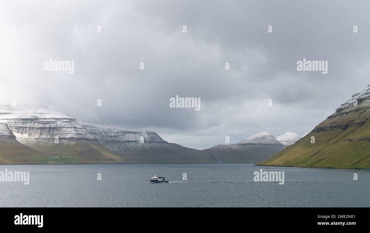 Bateau de pêche navigue à travers le paysage spectaculaire des îles Féroé. La nature des îles Féroé dans l'Atlantique Nord est pleine de beaux paysages. Banque D'Images
