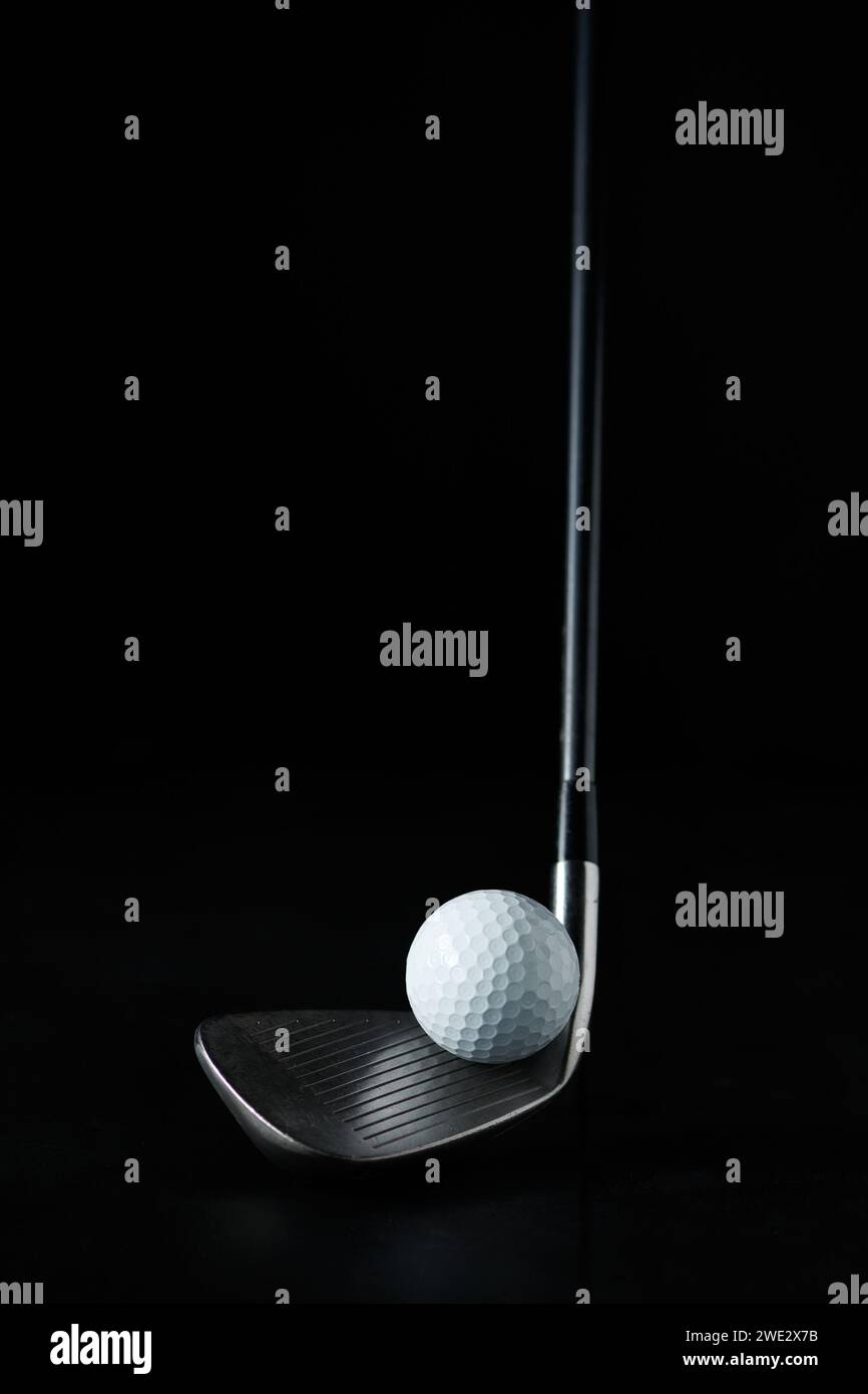 photo d'un bâton de golf avec le focus mis sur la balle de golf devant le bâton et avec un fond sombre Banque D'Images