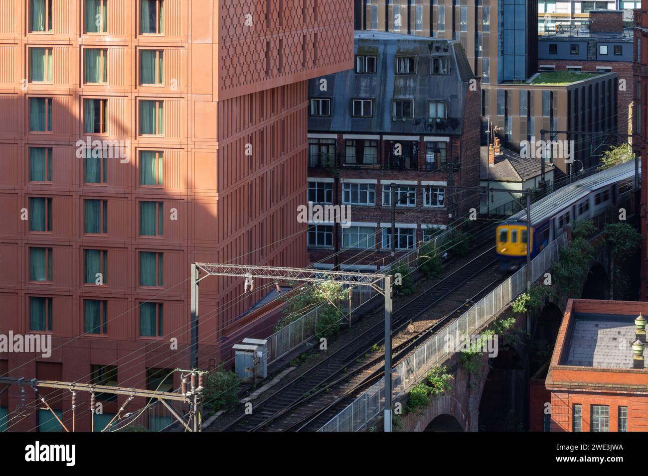 Un train circulant sur une ligne électrifiée au-dessus d'un viaduc victorien construit en brique à côté de l'hôtel Maldron, Manchester, Royaume-Uni Banque D'Images