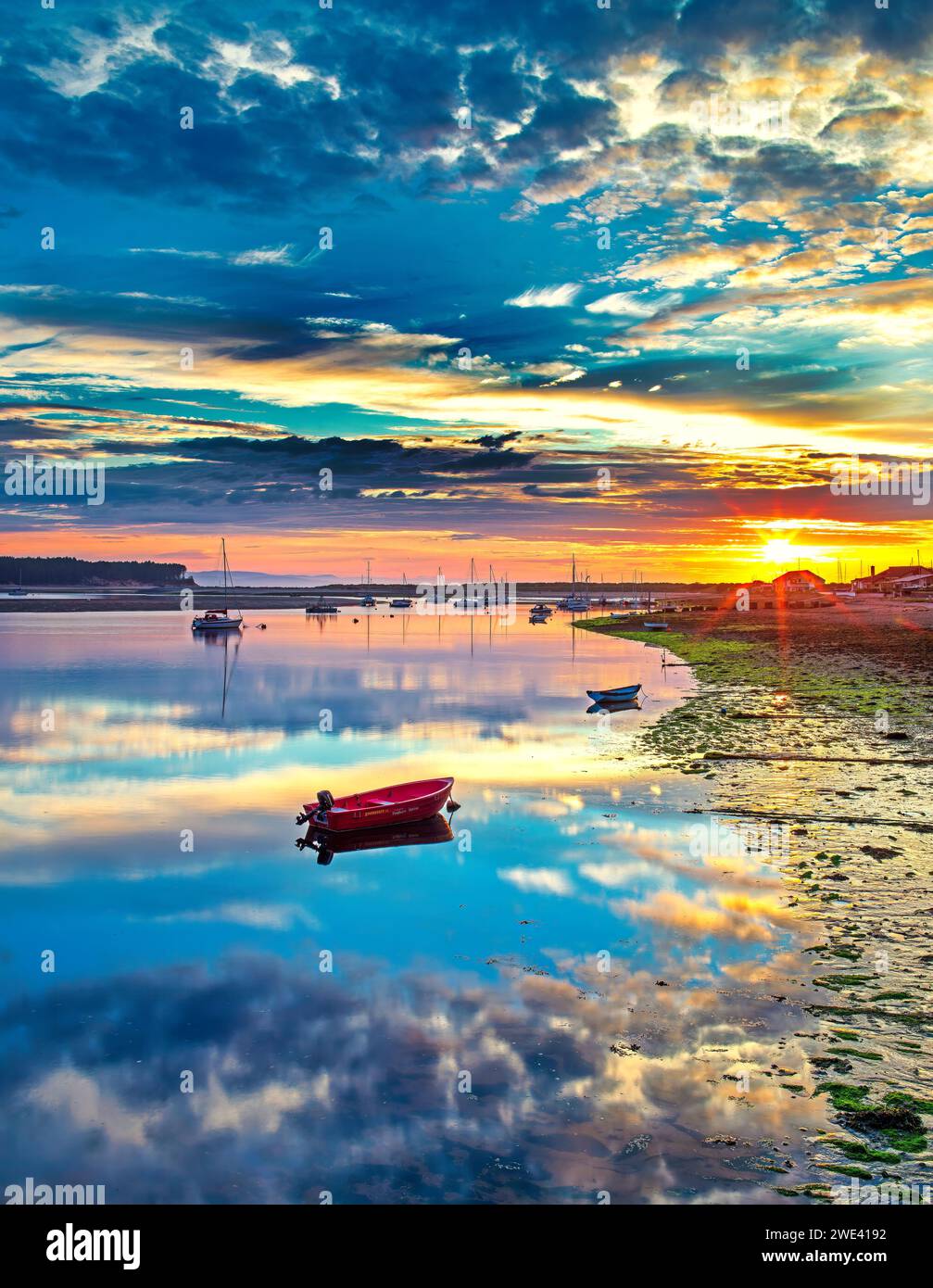 Coucher de soleil sur le port de Findforn à Findhorn sur le Moray Firth en Écosse regardant à travers les bateaux et les yachts amarrés à l'ancre avec un ciel de coucher de soleil glorieux Banque D'Images