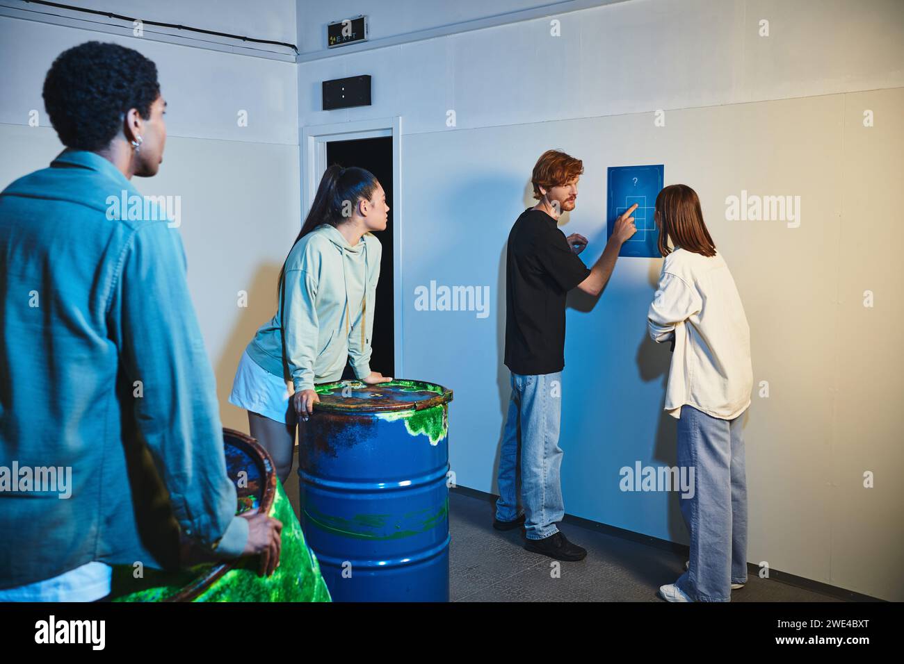 homme de redhead montrant l'indice à ses amis interraciaux pendant la quête dans la salle d'évasion, la résolution de mystère Banque D'Images