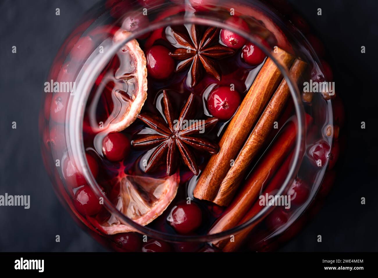 Vue de dessus du vin chaud dans le verre avec des tranches d'orange, bâton de cannelle, anis étoilé, romarin et canneberges en gros plan. Photographie culinaire Banque D'Images