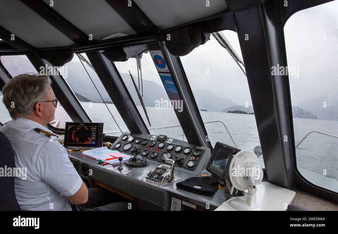 Capitaine de navire guidant un ferry à passagers avec l’aide d’un Simrad Autopilot sur le lac Manapouri, Aotearoa (Nouvelle-Zélande), te Waipounamu (Île du Sud) Banque D'Images