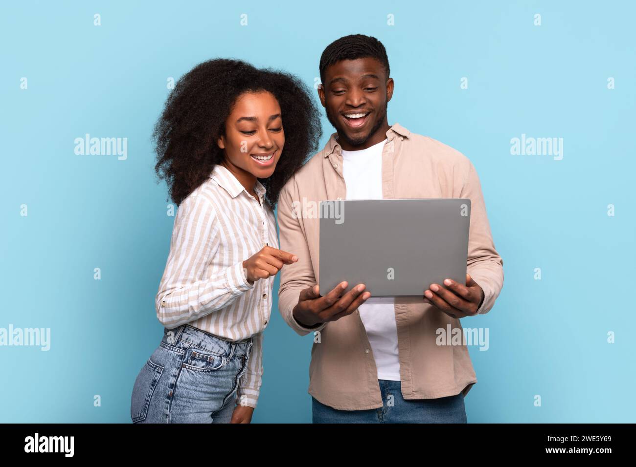 Couple noir s'engageant avec ordinateur portable ensemble sur fond bleu Banque D'Images