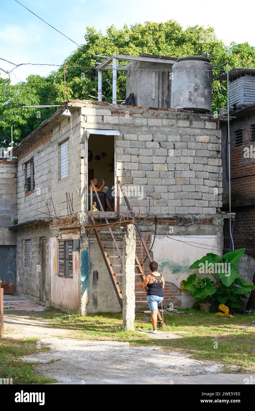 Une cubaine à la base d'un escalier métallique. La structure mène à une maison de style simple inachevée au deuxième étage. Banque D'Images