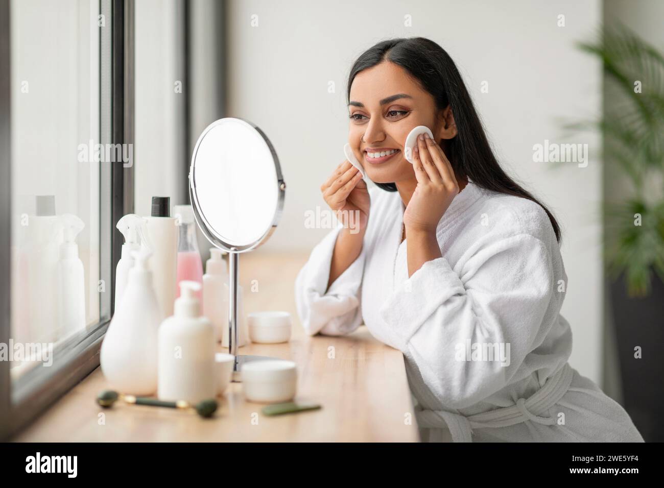 Jolie jeune femme indienne utilisant des tampons de coton à la salle de bain Banque D'Images