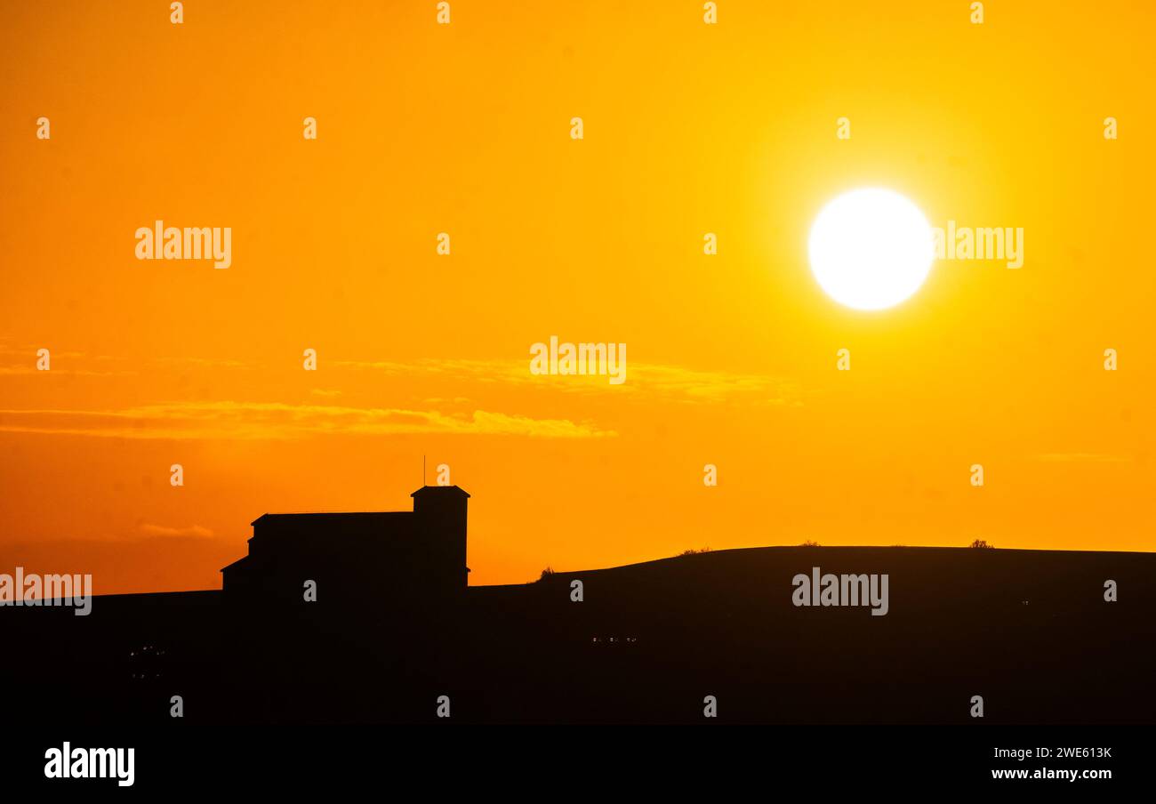 Coucher de soleil dans le village médiéval de Lerma sur une journée de chaleur torride avec la silhouette d'une montagne et une église dans les derniers rayons du soleil de l'après-midi. Banque D'Images