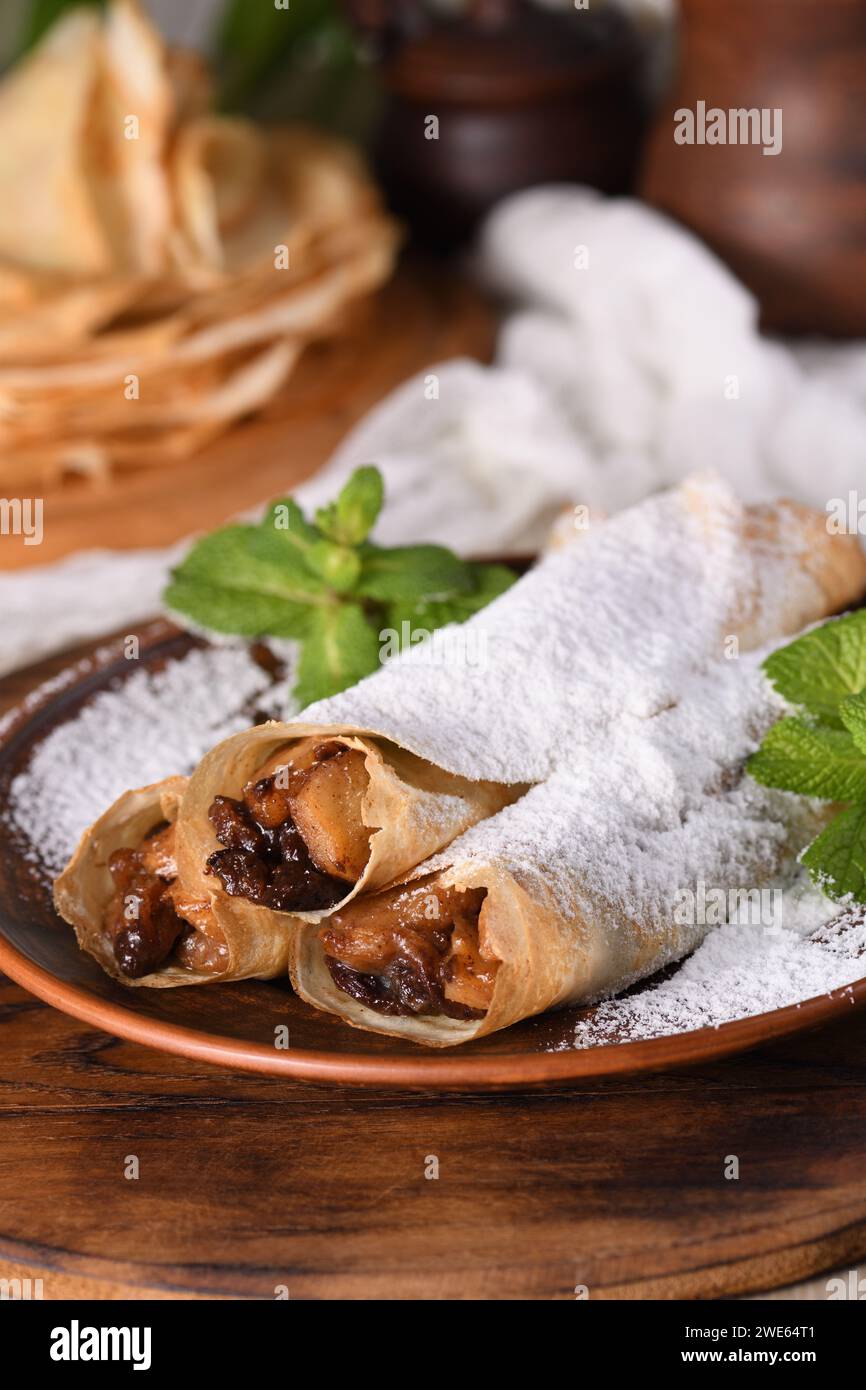 Crêpes fines maison. Les pommes sont cuites dans une sauce caramel beurrée avec des raisins secs et de la cannelle et farcies en une fine crêpe. Banque D'Images