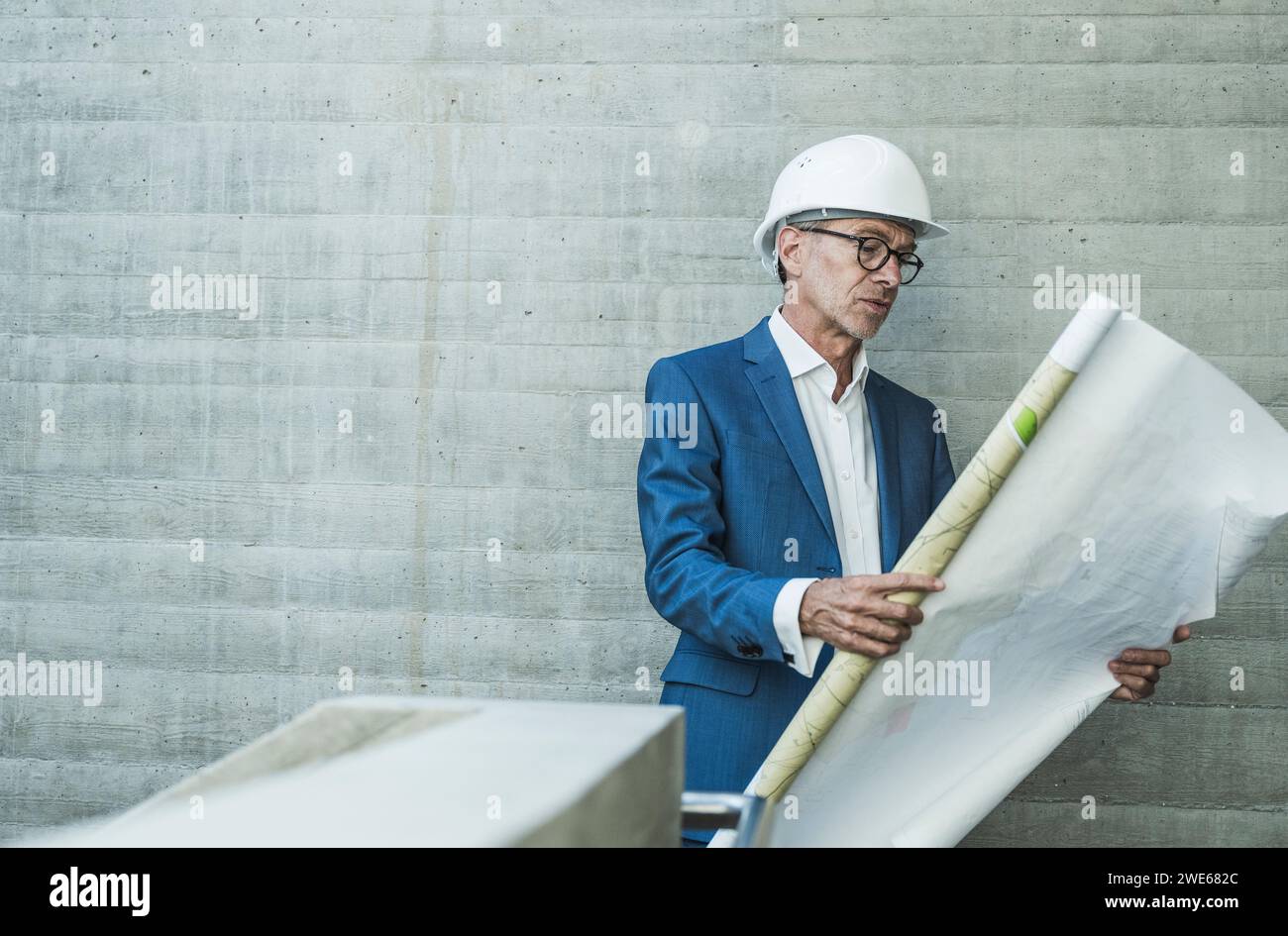 Ingénieur portant un casque dur et examinant le plan près du mur Banque D'Images