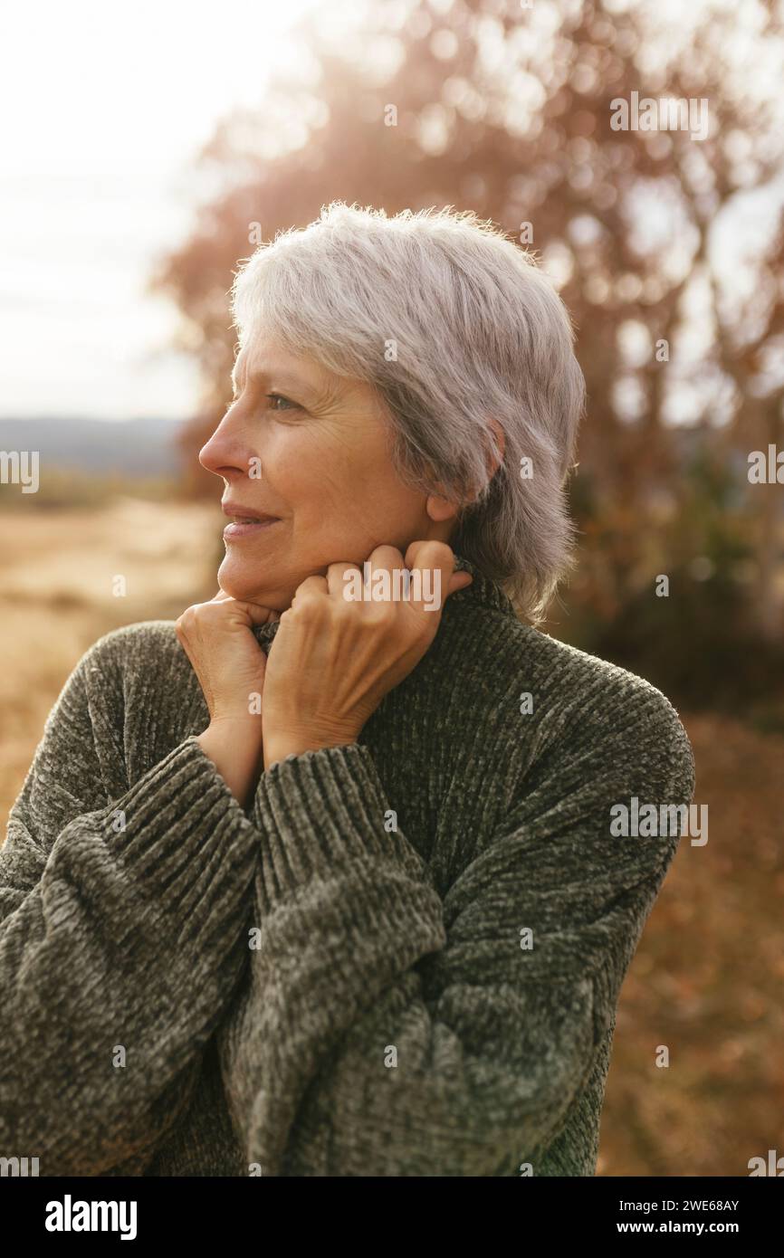 Femme mûre réfléchie avec les cheveux gris debout dans la nature Banque D'Images