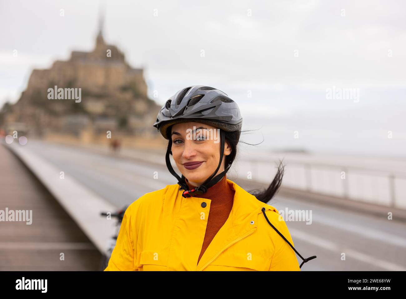 Femme souriante avec casque de vélo dans la rue Banque D'Images