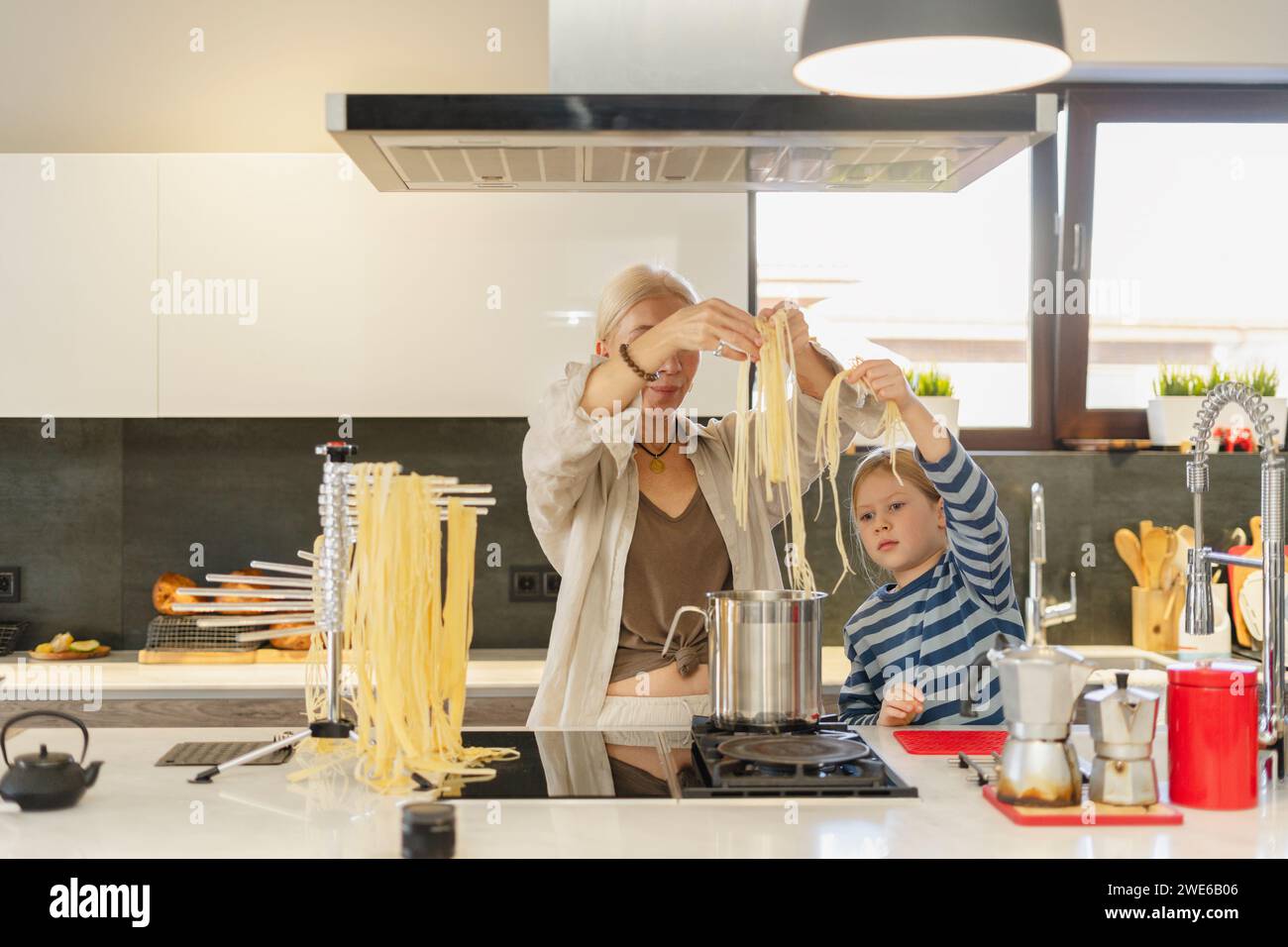 Grand-mère et petite-fille faisant bouillir des spaghettis dans une poêle à la maison Banque D'Images
