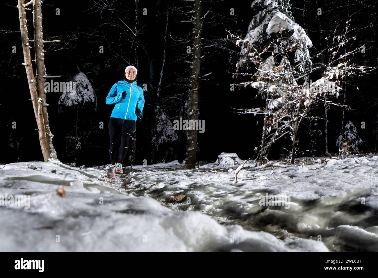 Jeune femme courant dans la forêt d'hiver la nuit Banque D'Images