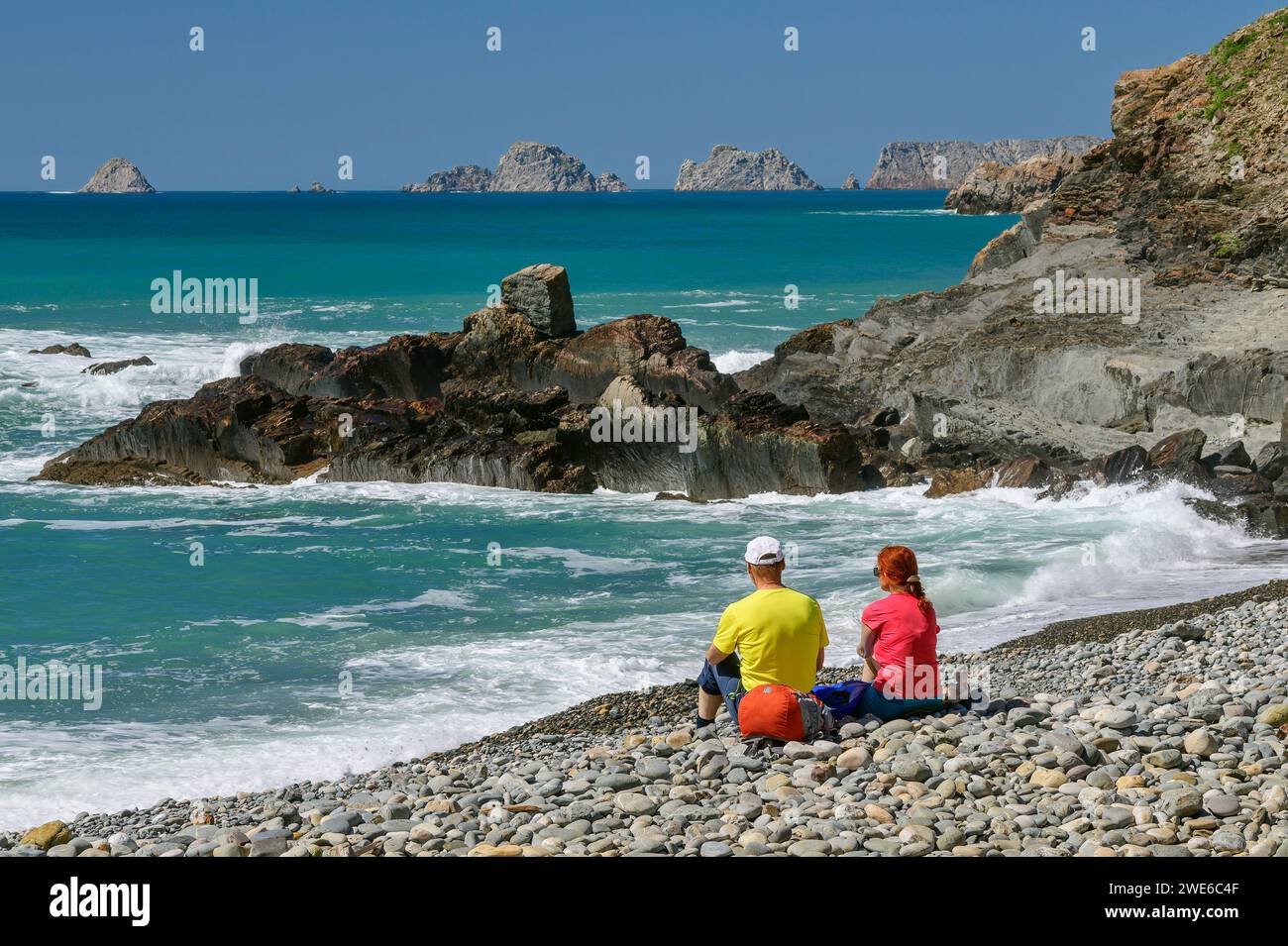 France, Bretagne, deux randonneurs se détendant sur la plage rocheuse de Porzh Mel Banque D'Images