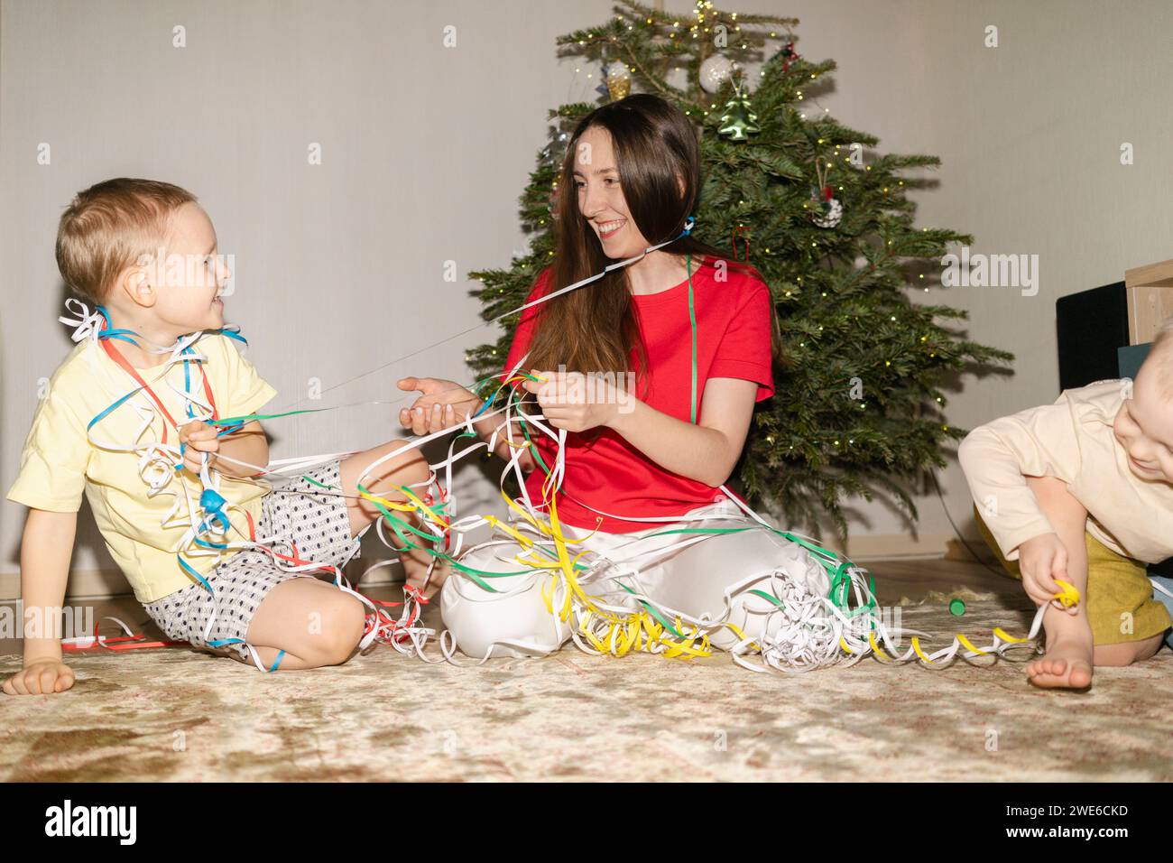 Mère souriante et fils s'amusant avec des poppers de fête à la maison Banque D'Images