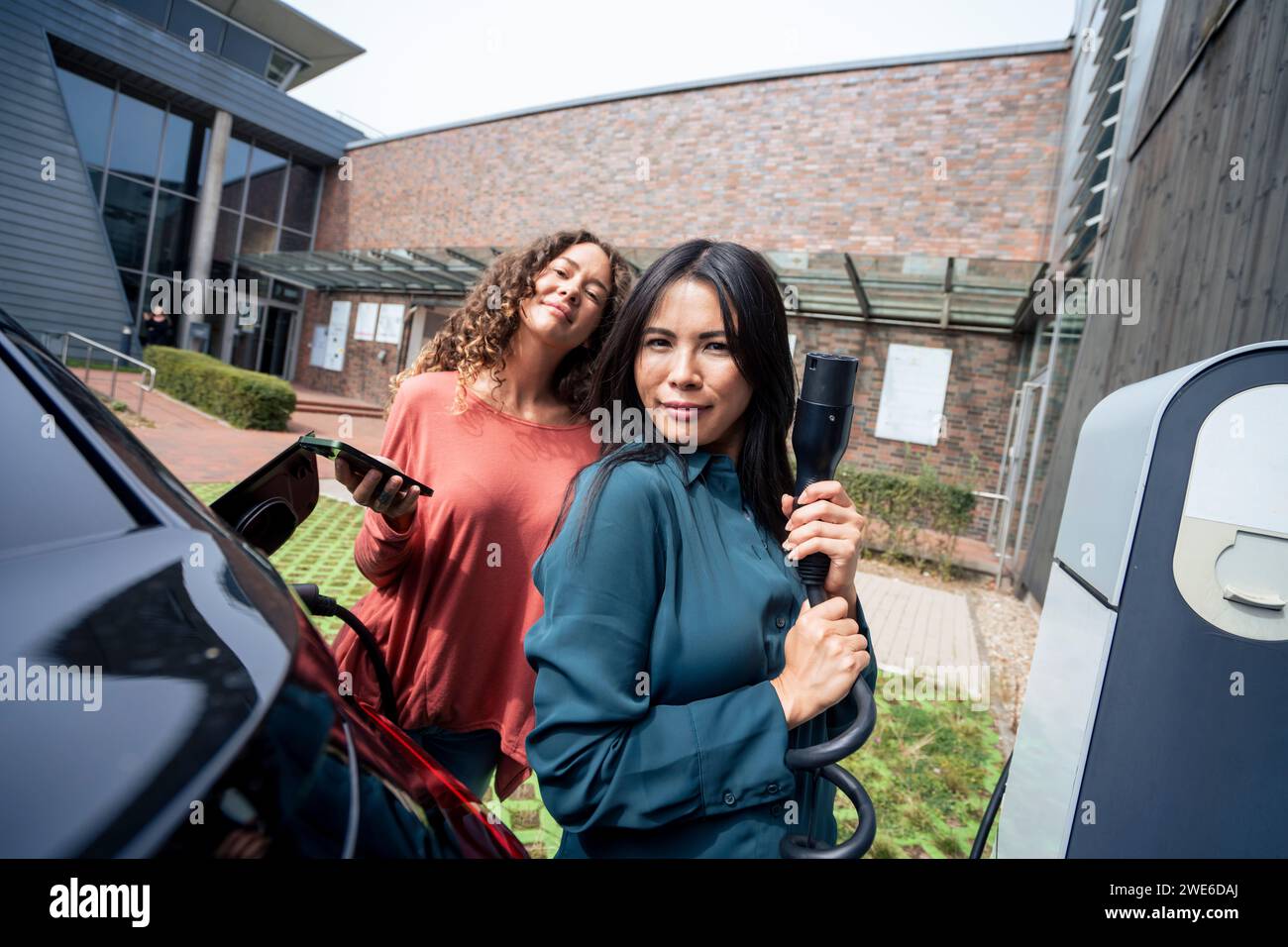 Femme avec prise électrique par un ami tenant le téléphone intelligent Banque D'Images
