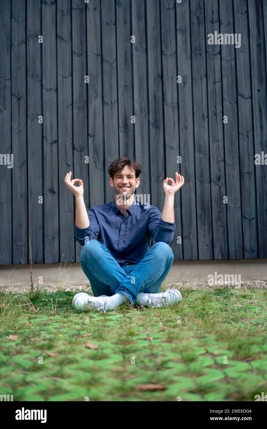 Homme souriant assis en position lotus sur l'herbe Banque D'Images