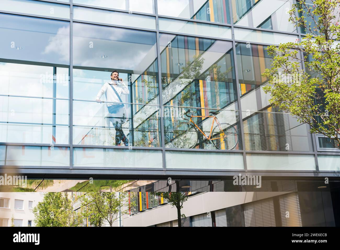Homme d'affaires debout près du mur de verre et parlant sur le téléphone intelligent Banque D'Images